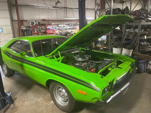 Green classic car with its hood open