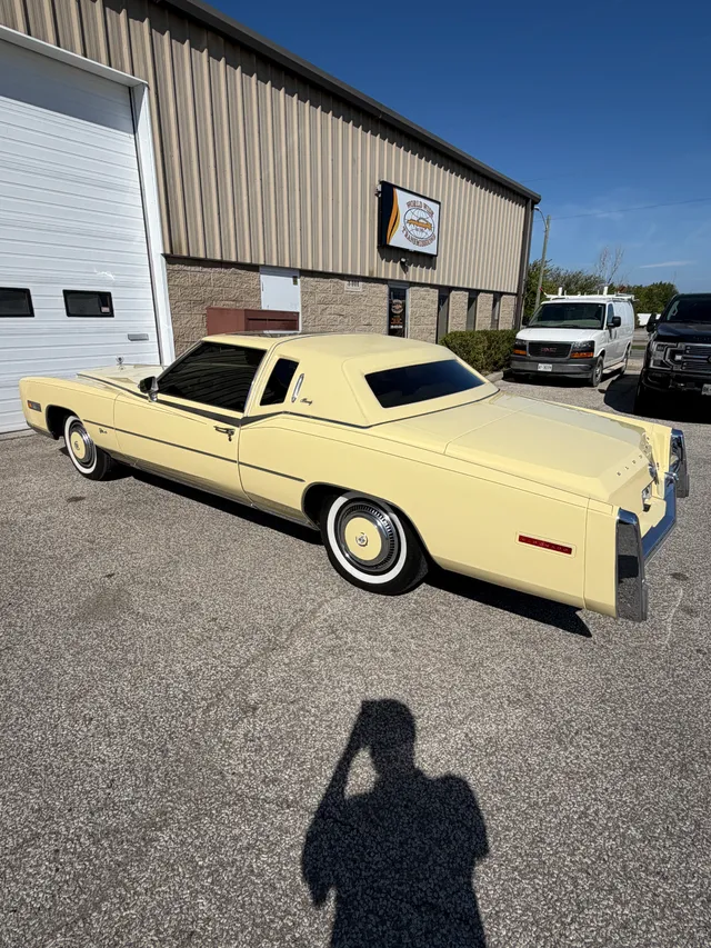 Pale yellow classic coupe outside the shop